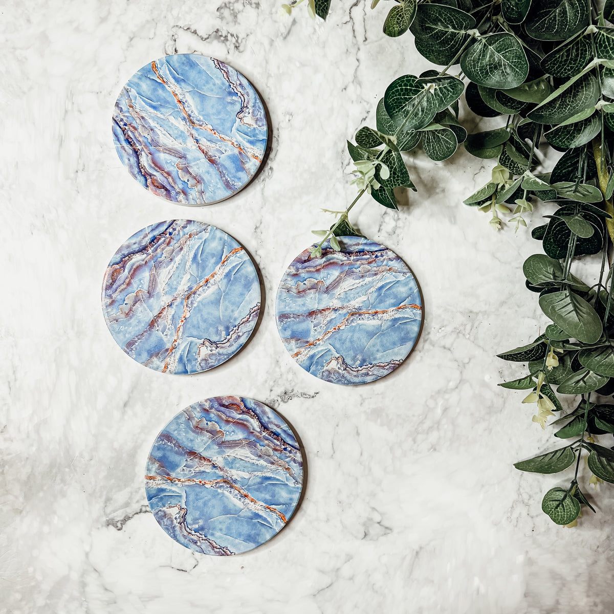 Set of four luxurious Marble Blue Coasters with a watercolor effect, featuring shades of blue and gold accents, displayed in a brown box.