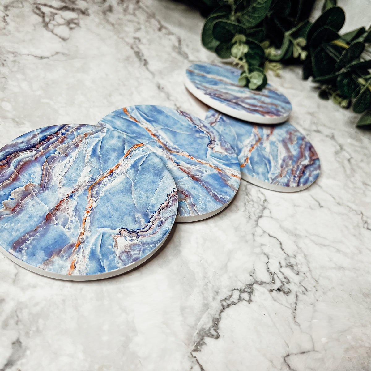 Set of four luxurious Marble Blue Coasters with a watercolor effect, featuring shades of blue and gold accents, displayed in a brown box.