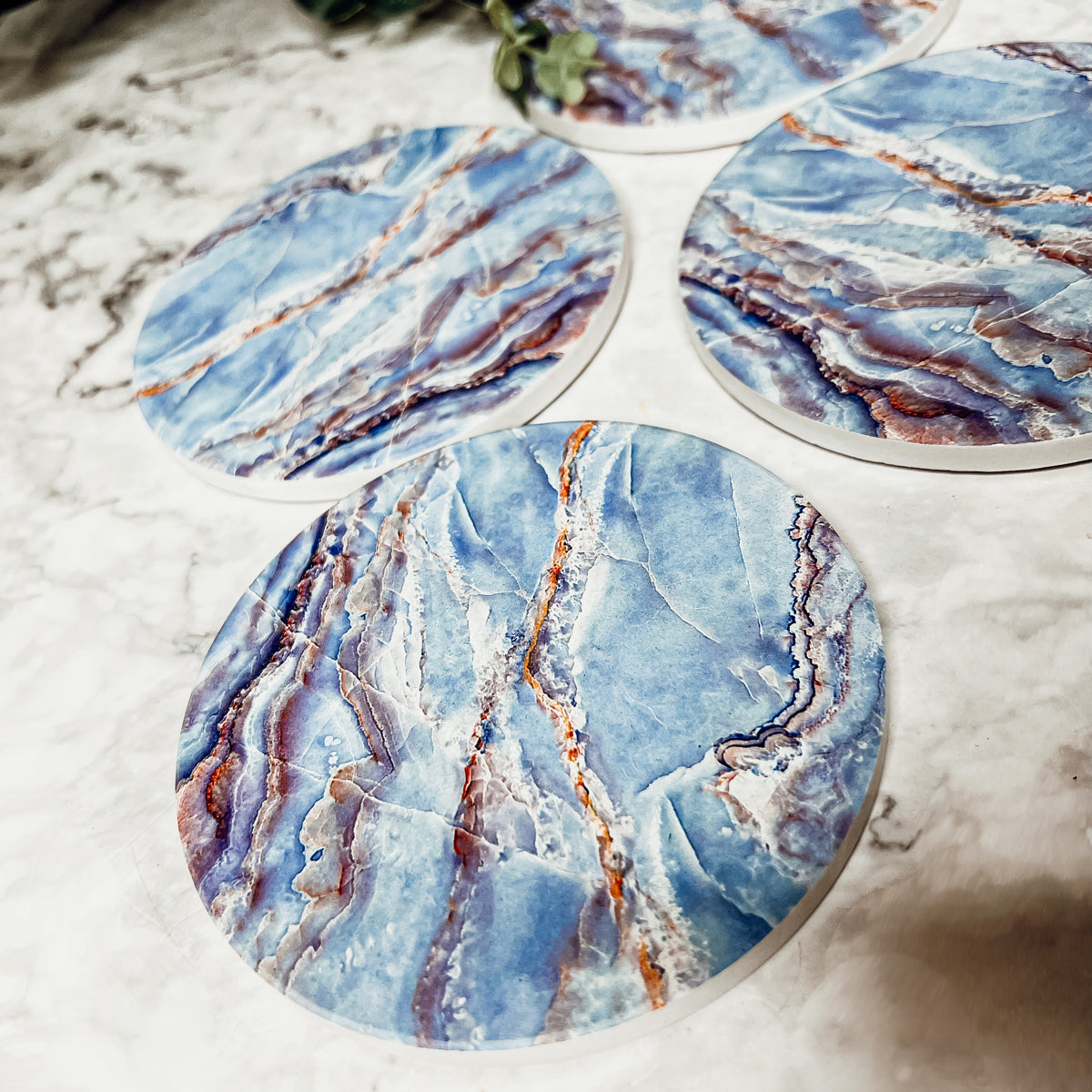 Set of four luxurious Marble Blue Coasters with a watercolor effect, featuring shades of blue and gold accents, displayed in a brown box.