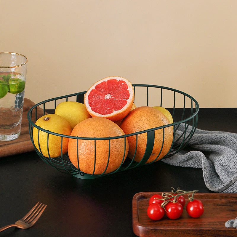 A stylish metal hollowed out fruit and vegetable snack tray bowl basket in dark green and gold, showcasing a variety of fresh fruits and snacks.