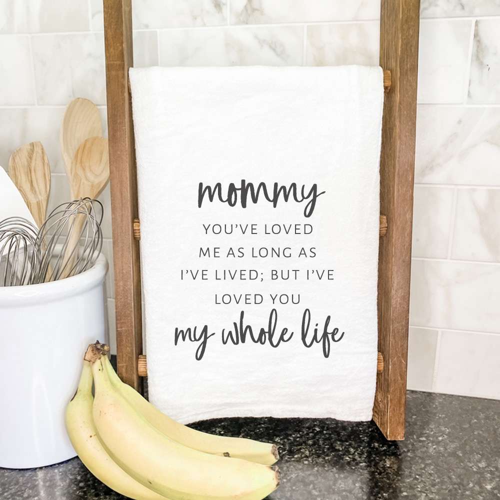 A beautifully designed cotton tea towel featuring the phrase 'Mom / Mommy Loved You My Whole Life', showcasing vibrant colors and hemmed edges.