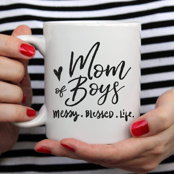 A ceramic coffee mug with the phrase 'Mom Of Boys. Messy. Blessed. Life.' printed in a playful font, showcasing a fun and relatable design for mothers.