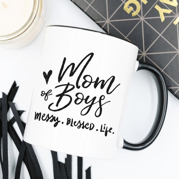 A ceramic coffee mug with the phrase 'Mom Of Boys. Messy. Blessed. Life.' printed in a playful font, showcasing a fun and relatable design for mothers.