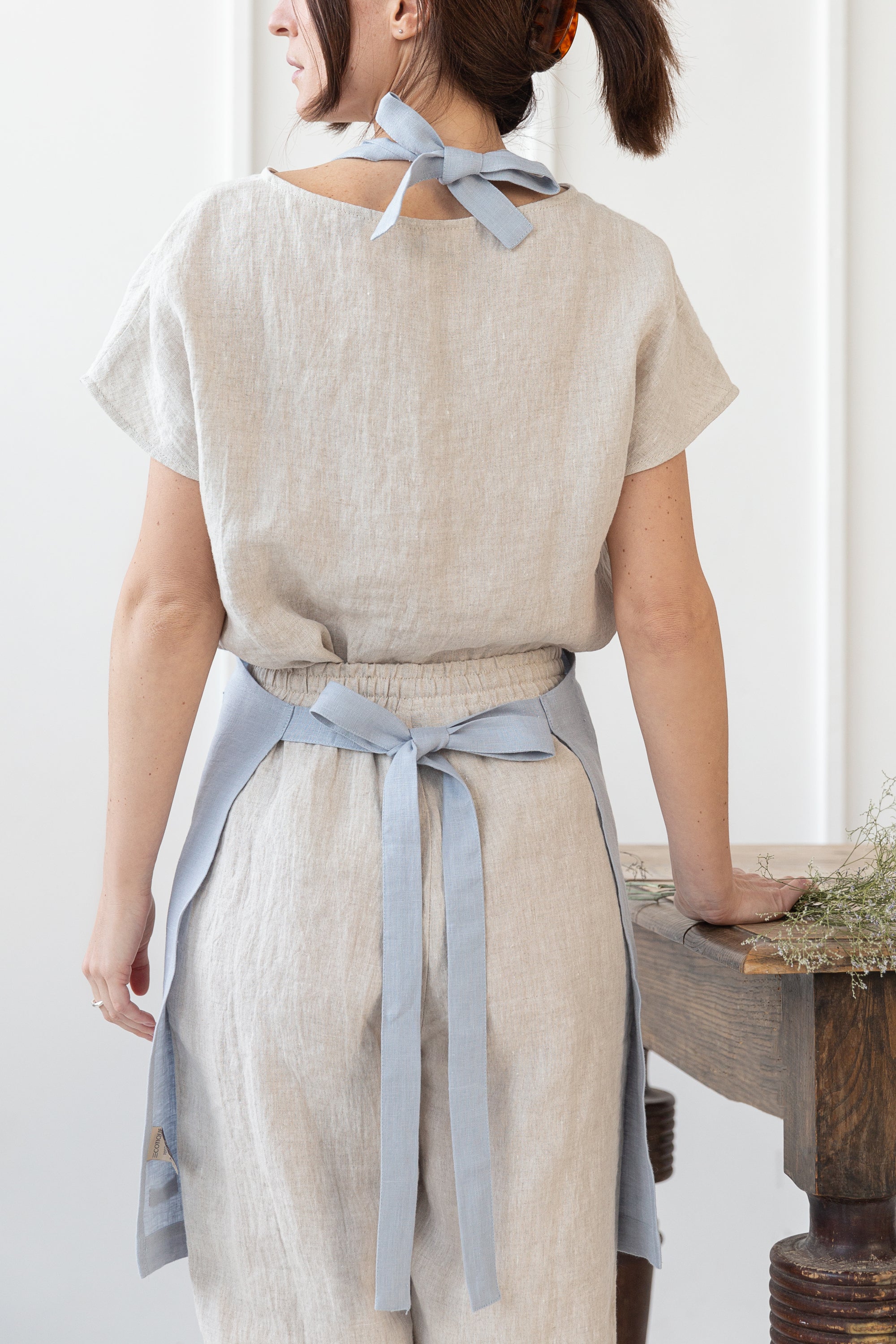 Moss Green linen apron with adjustable back ties and front pockets, showcasing its elegant design and functionality.