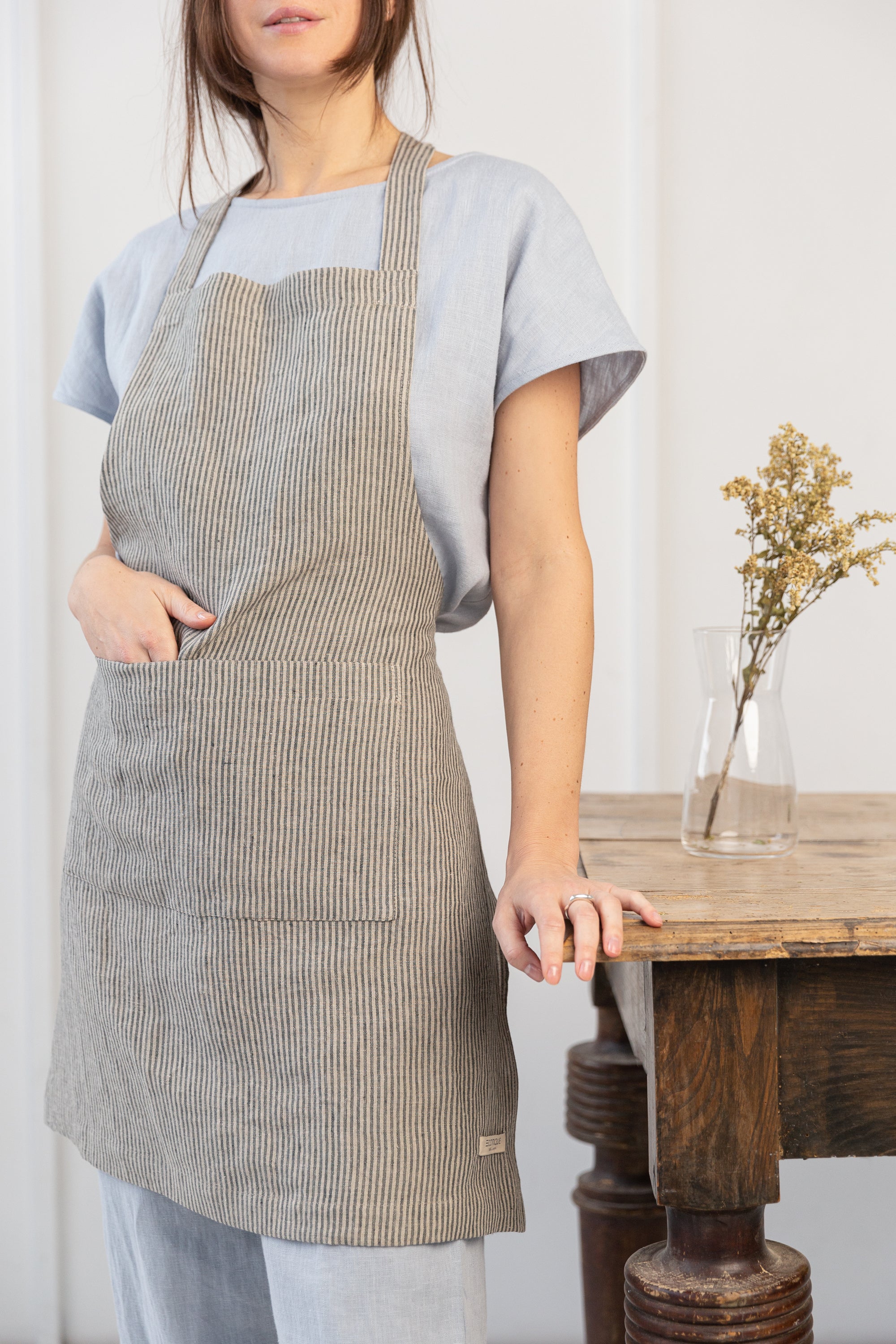 Moss Green linen apron with adjustable back ties and front pockets, showcasing its elegant design and functionality.