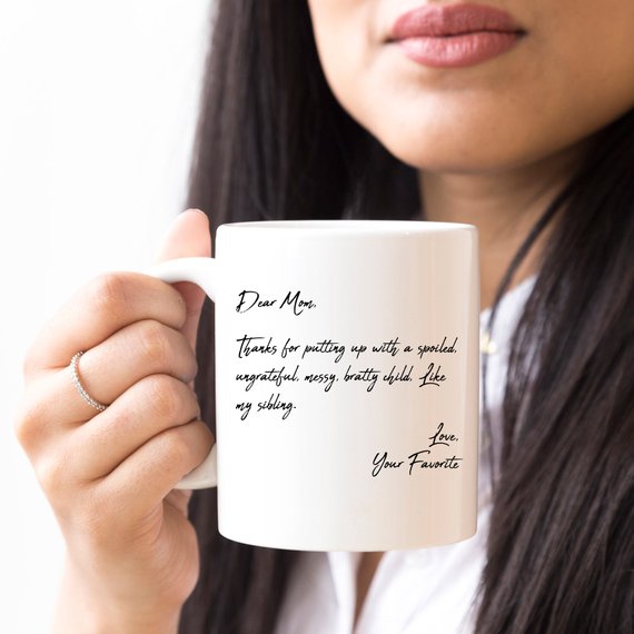 A humorous coffee mug with the text 'Dear Mom, Thanks 4 Putting Up With A S, Your Favorite', featuring a stylish design and a comfortable handle.