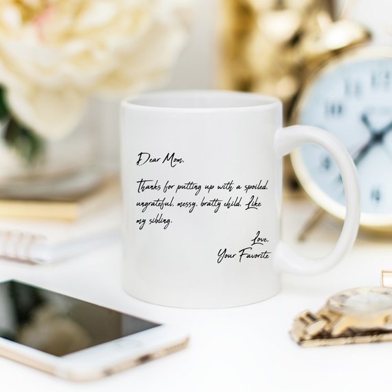 A humorous coffee mug with the text 'Dear Mom, Thanks 4 Putting Up With A S, Your Favorite', featuring a stylish design and a comfortable handle.