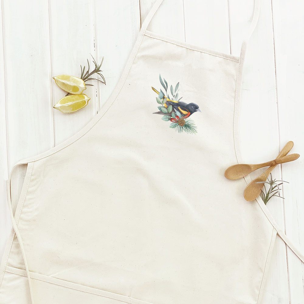 Oriole Women's Apron featuring a fall birds design, made from cotton canvas with natural twill ties and a divided front pocket.