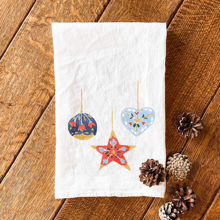 A vibrant cotton tea towel featuring beautiful ornament designs, perfect for kitchen use, measuring 27 inches square.