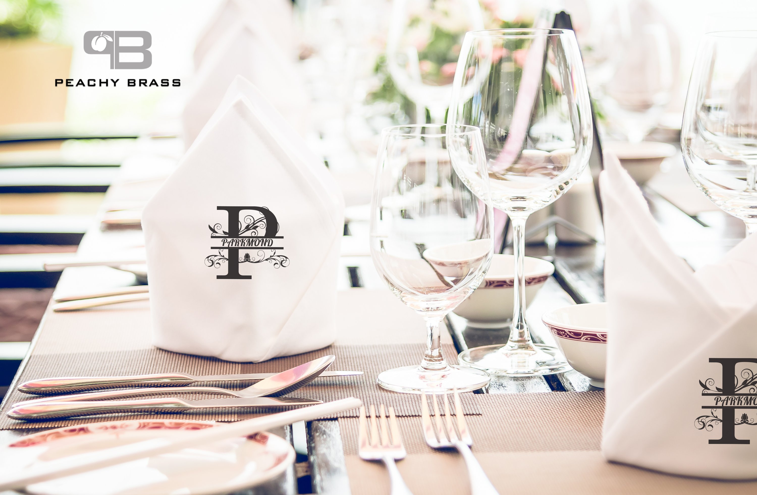 Set of six personalized cloth napkins in white with black initials, elegantly folded on a dining table.