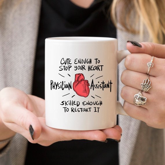 A humorous coffee mug designed for Physician Assistants, featuring the phrase 'Cute Enough To Stop Your Heart' in a vibrant print on a white ceramic background.