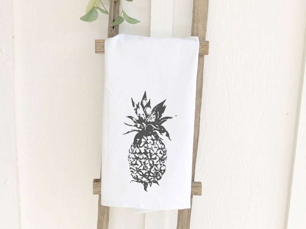 A vibrant pineapple design on a 100% cotton tea towel, showcasing its absorbent texture and hemmed edges.