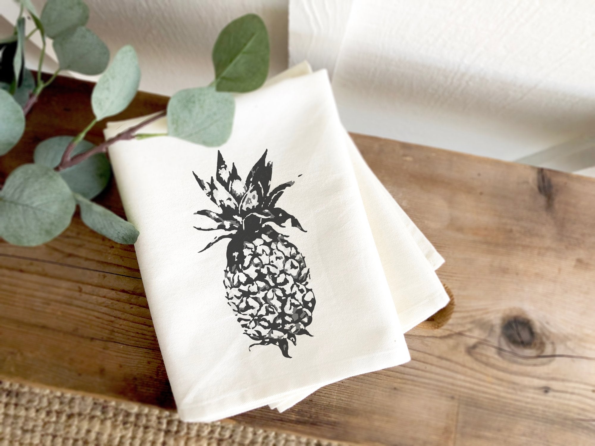 A vibrant pineapple design on a 100% cotton tea towel, showcasing its absorbent texture and hemmed edges.