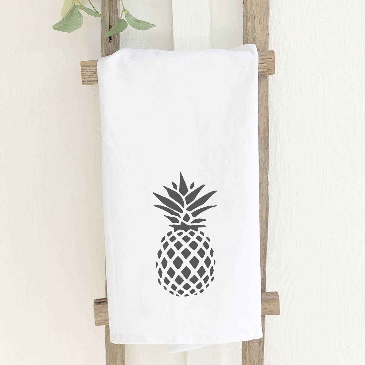 A vibrant cotton tea towel featuring a pineapple stamp design, showcasing its absorbent texture and hemmed edges.