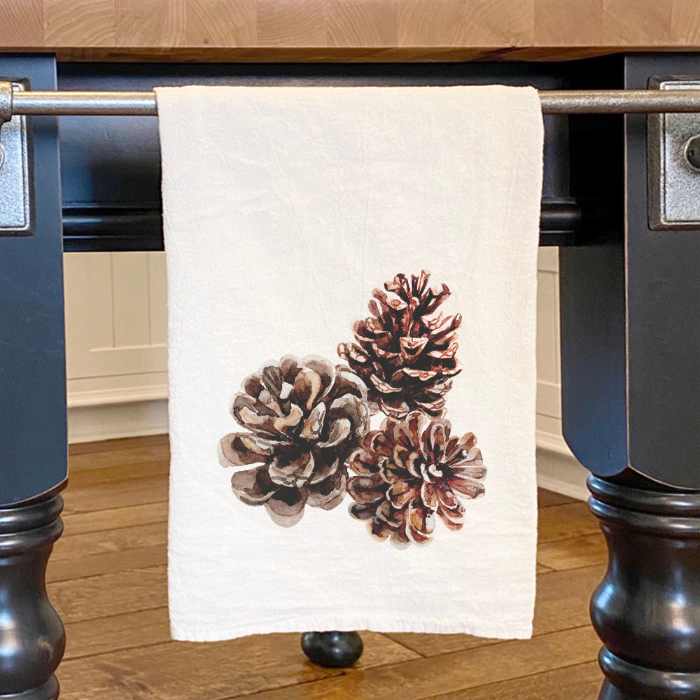 A vibrant cotton tea towel featuring a beautiful pinecone design, perfect for kitchen use.