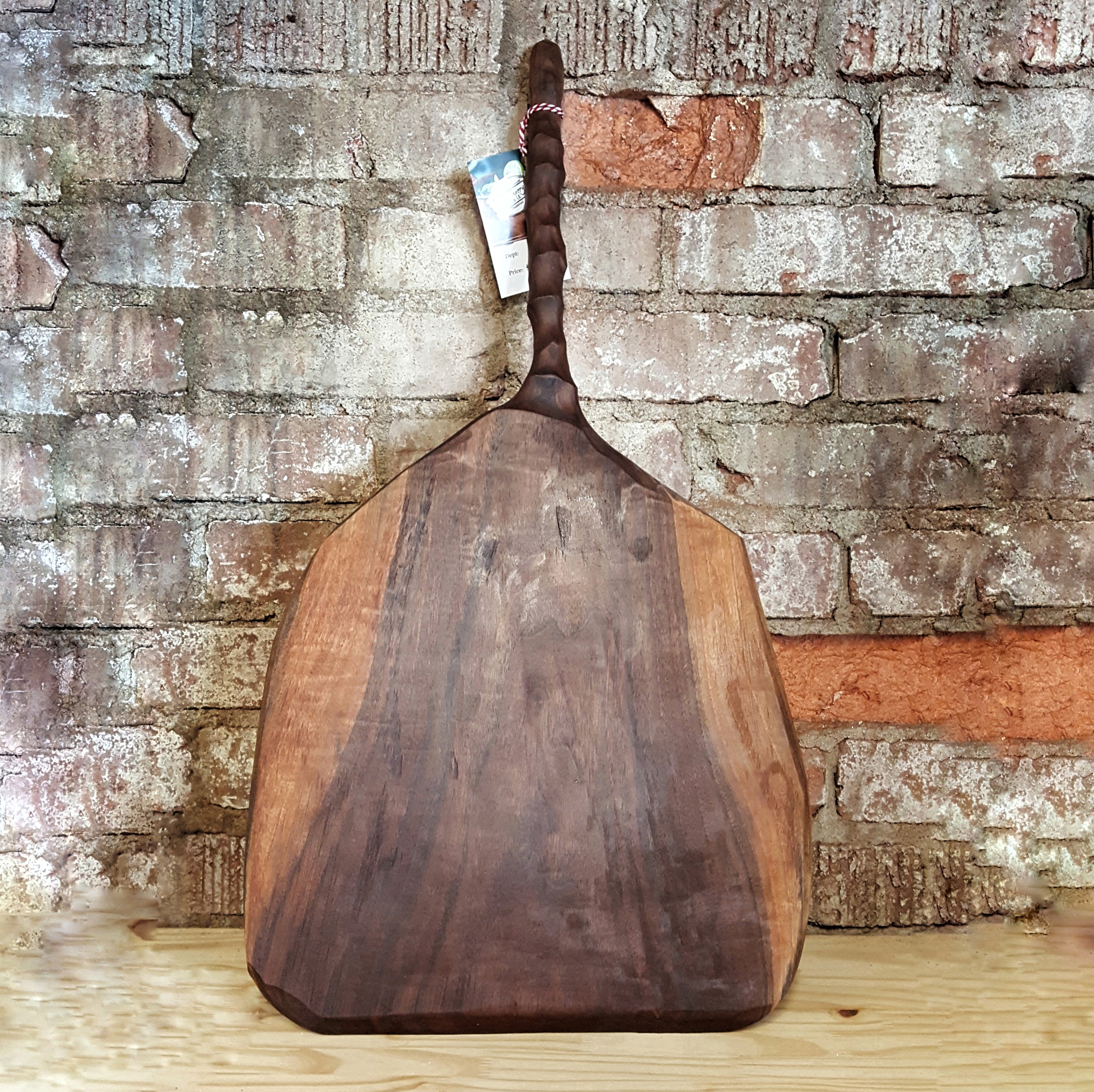 Wooden pizza paddle with handcarved chiseled handle, made from walnut lumber, showcasing its natural finish.