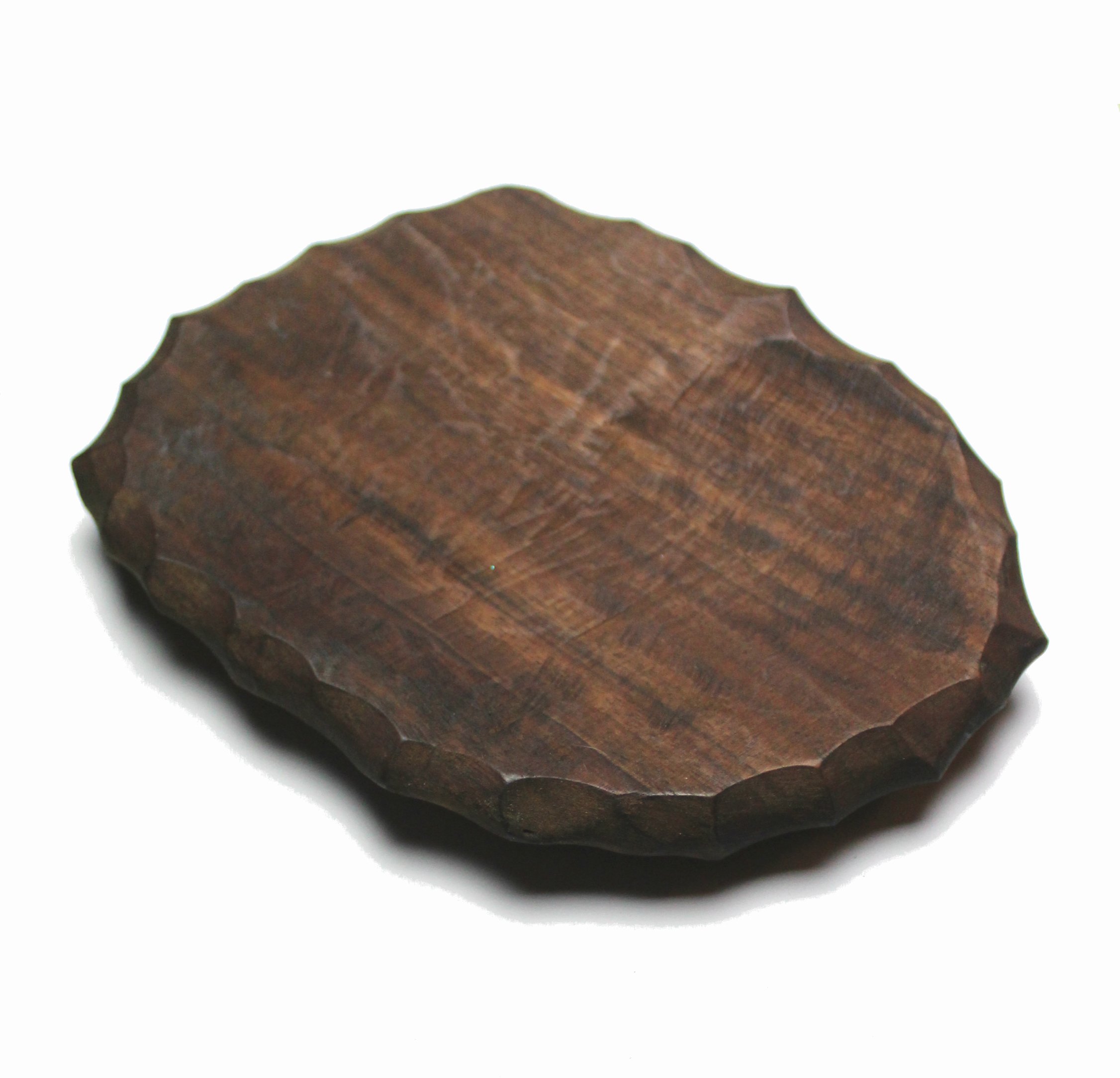 Small handcarved wood plate with a chiseled edge, showcasing its unique craftsmanship and natural wood grain.