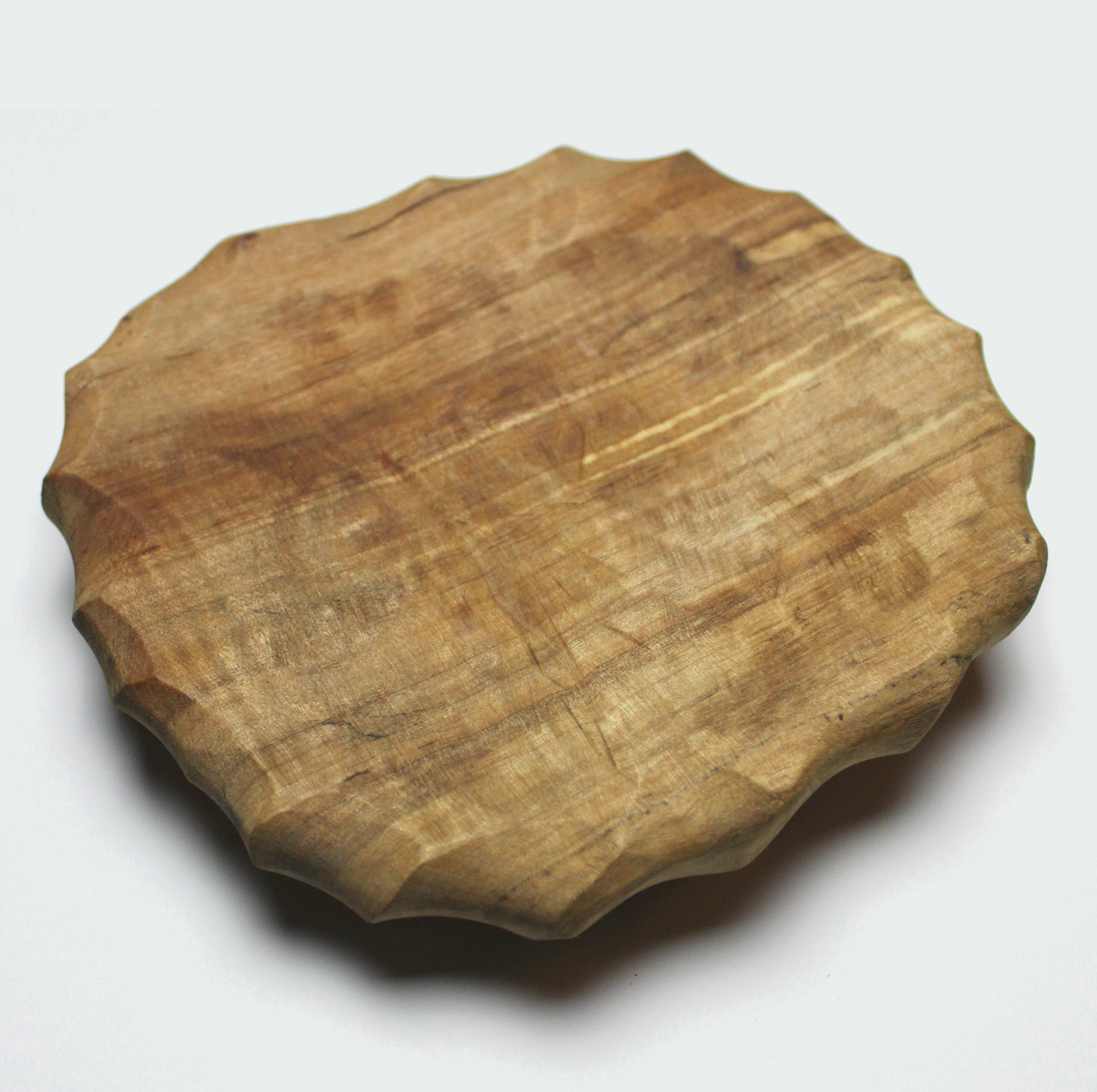 Small handcarved wood plate with a chiseled edge, showcasing its unique craftsmanship and natural wood grain.