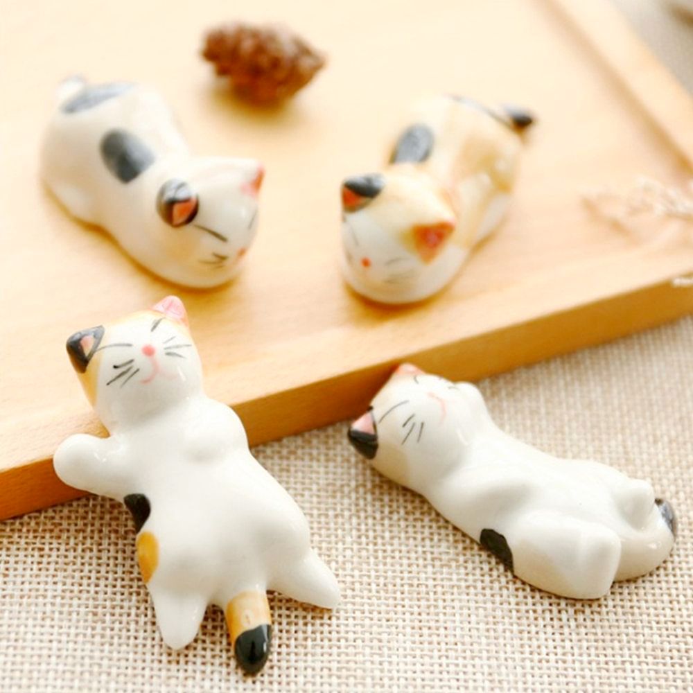 A set of six porcelain cat chopstick holders in various adorable poses, perfect for dining decor.