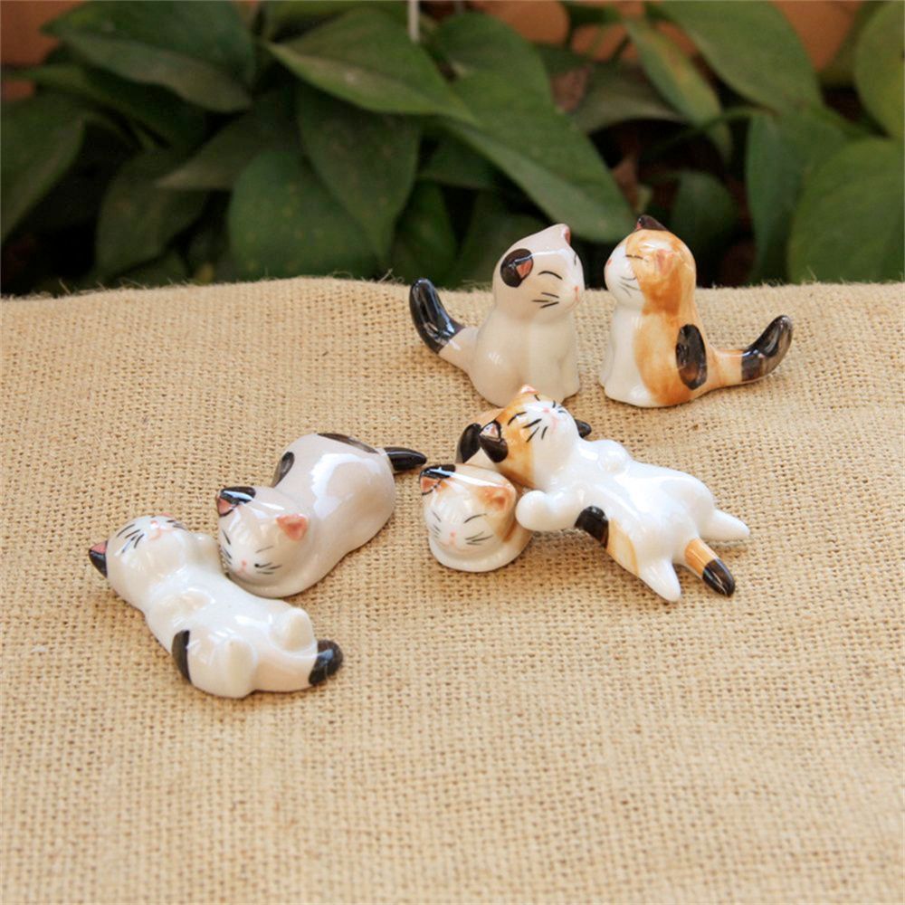 A set of six porcelain cat chopstick holders in various adorable poses, perfect for dining decor.