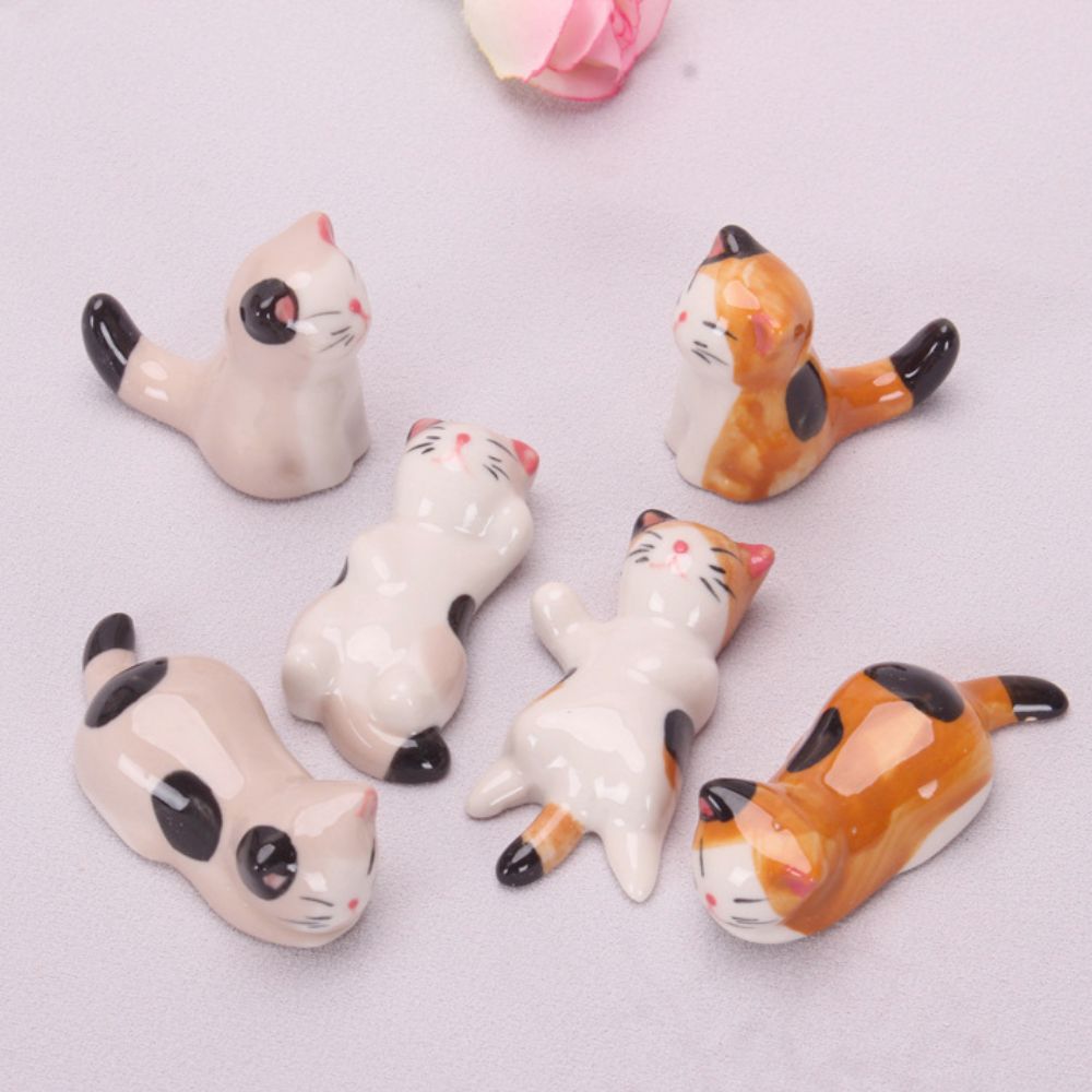 A set of six porcelain cat chopstick holders in various adorable poses, perfect for dining decor.