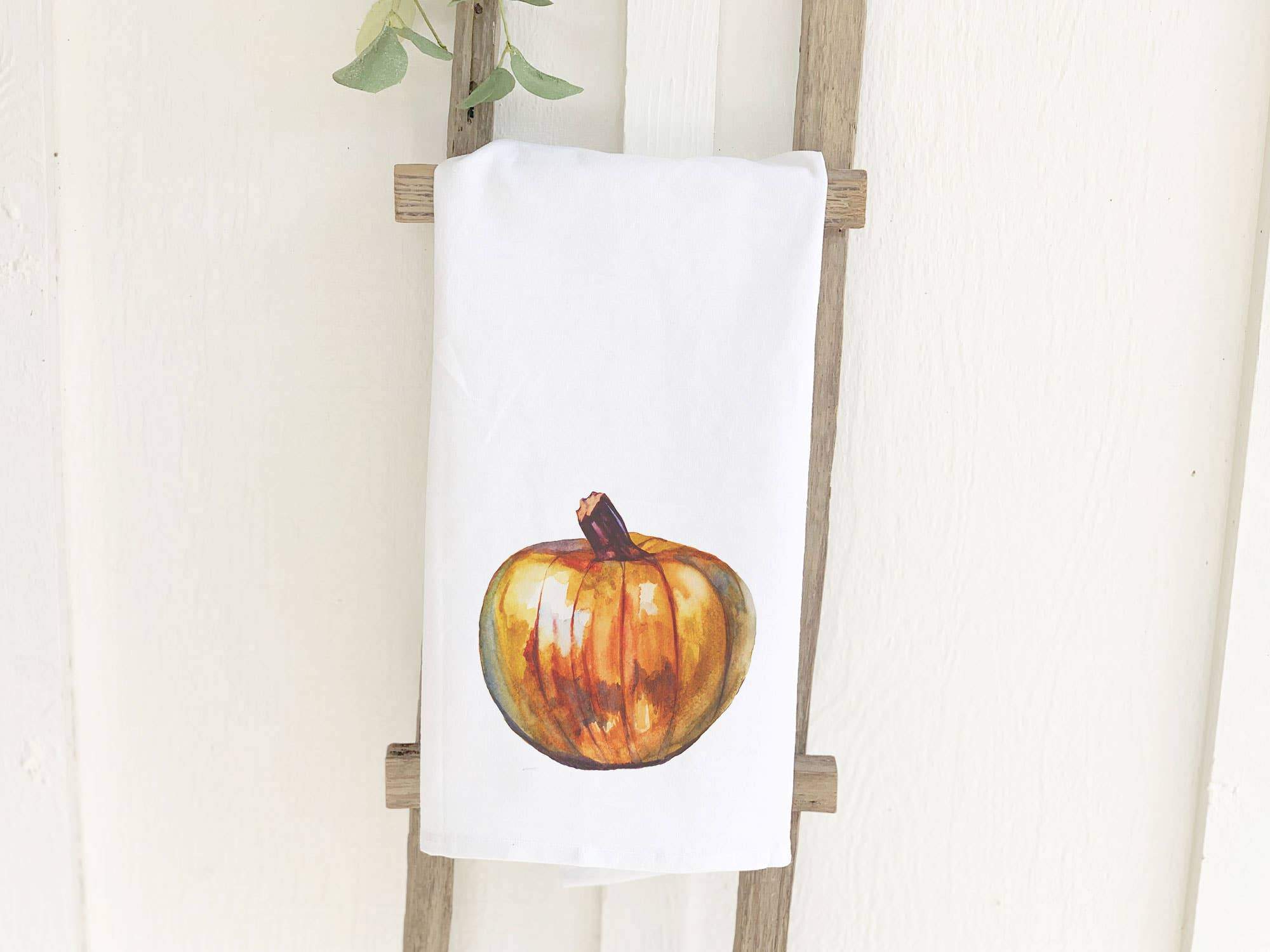 A vibrant pumpkin-themed cotton tea towel, showcasing its absorbent fabric and hemmed edges, perfect for kitchen use.