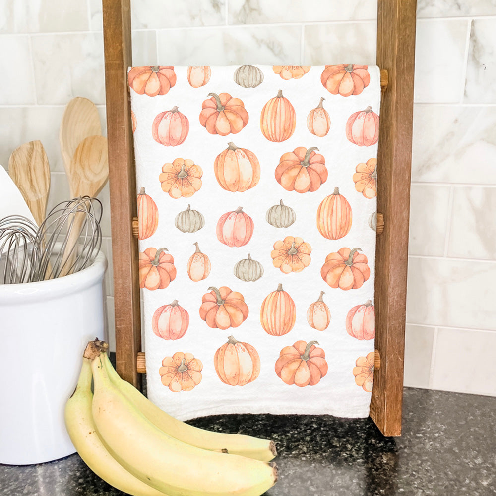 A vibrant cotton tea towel featuring a pumpkin pattern, showcasing its absorbent fabric and hemmed edges, perfect for kitchen use.