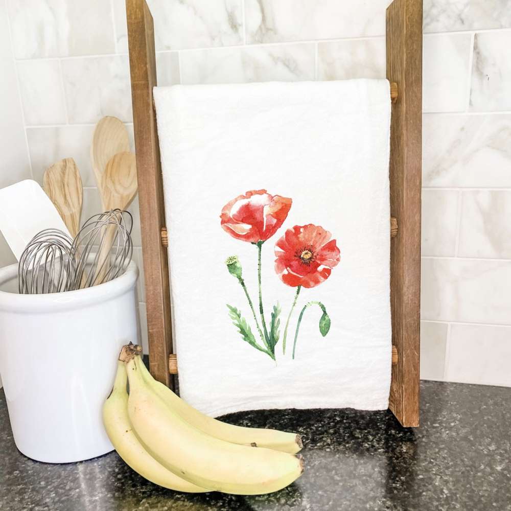 A vibrant Red Poppy Cotton Tea Towel featuring a beautiful floral design, made from 100% absorbent cotton, displayed on a kitchen countertop.