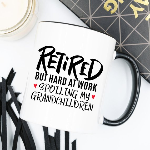 A humorous coffee mug with the phrase 'Retired But Hard At Work Spoiling My Grandchildren', showcasing a playful design perfect for grandparents.