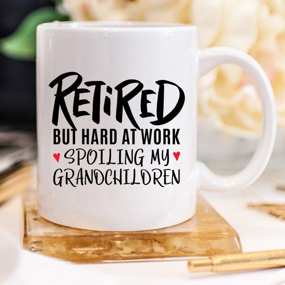 A humorous coffee mug with the phrase 'Retired But Hard At Work Spoiling My Grandchildren', showcasing a playful design perfect for grandparents.