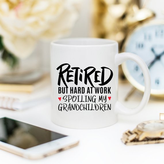 A humorous coffee mug with the phrase 'Retired But Hard At Work Spoiling My Grandchildren', showcasing a playful design perfect for grandparents.