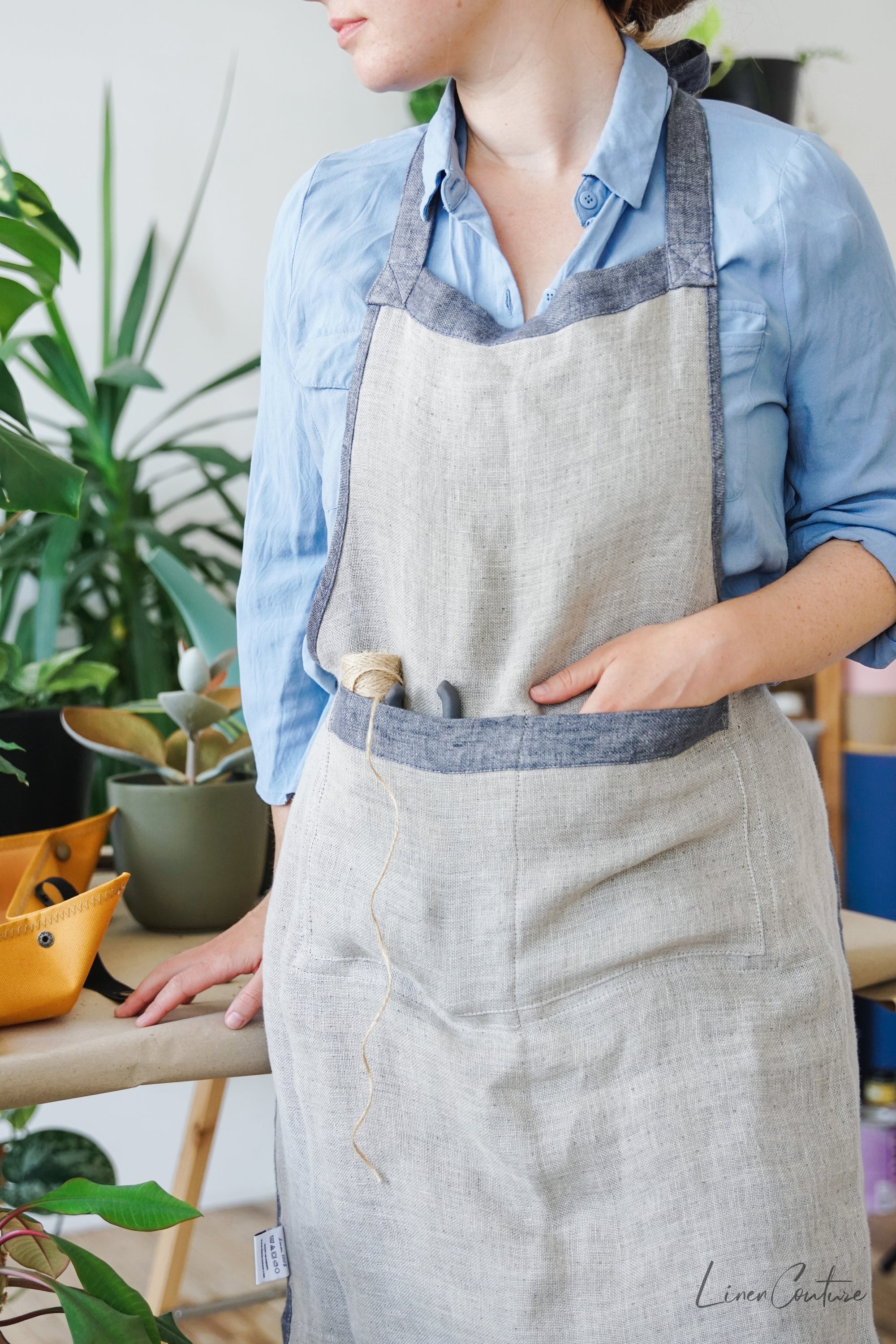 Reversible double cloth linen apron in grey and natural colors, featuring four pockets and back ties for adjustable fit.