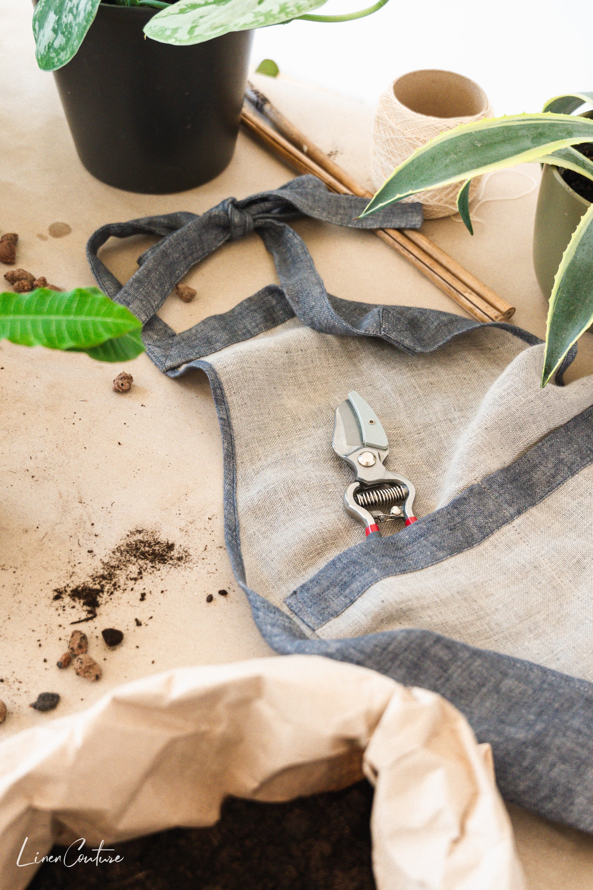 Reversible double cloth linen apron in grey and natural colors, featuring four pockets and back ties for adjustable fit.