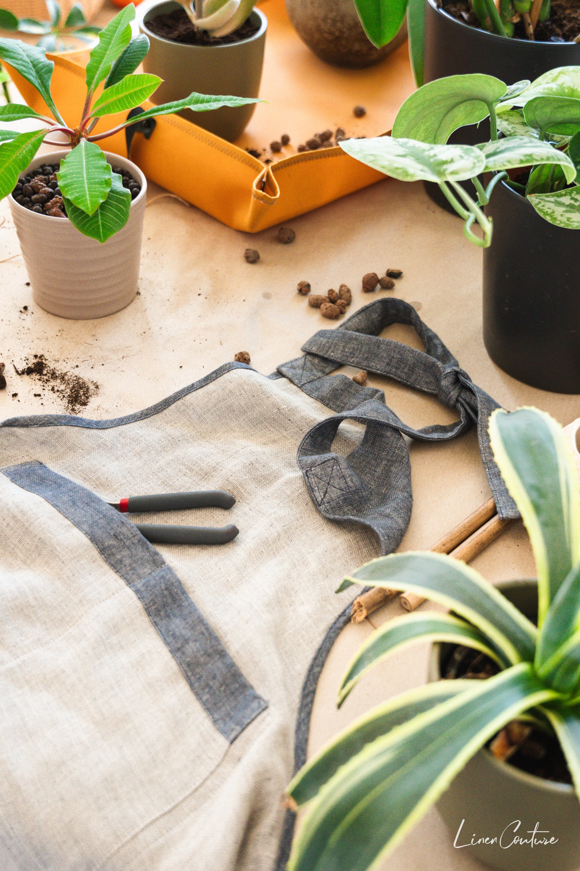 Reversible double cloth linen apron in grey and natural colors, featuring four pockets and back ties for adjustable fit.