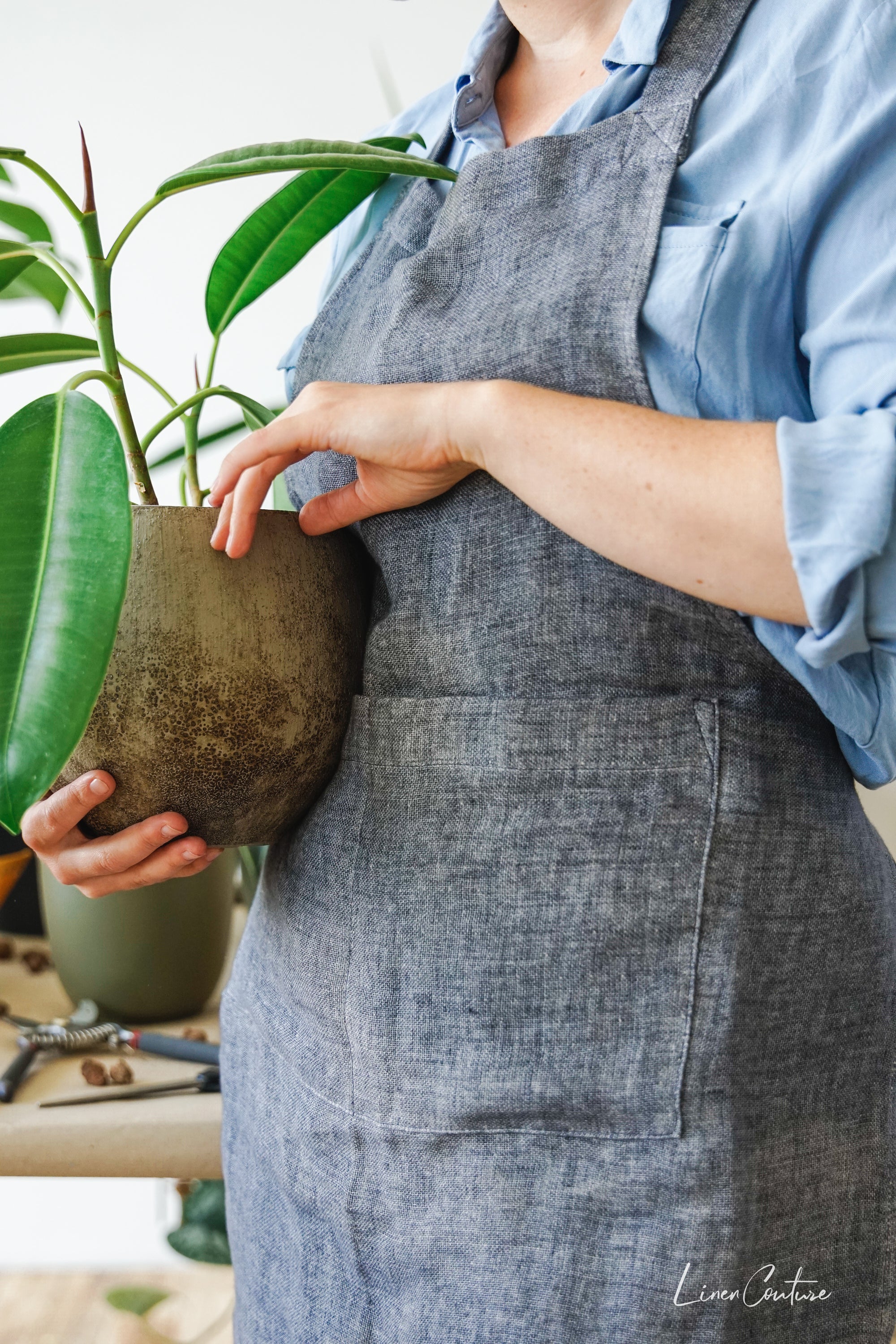 Reversible double cloth linen apron in grey and natural colors, featuring four pockets and back ties for adjustable fit.