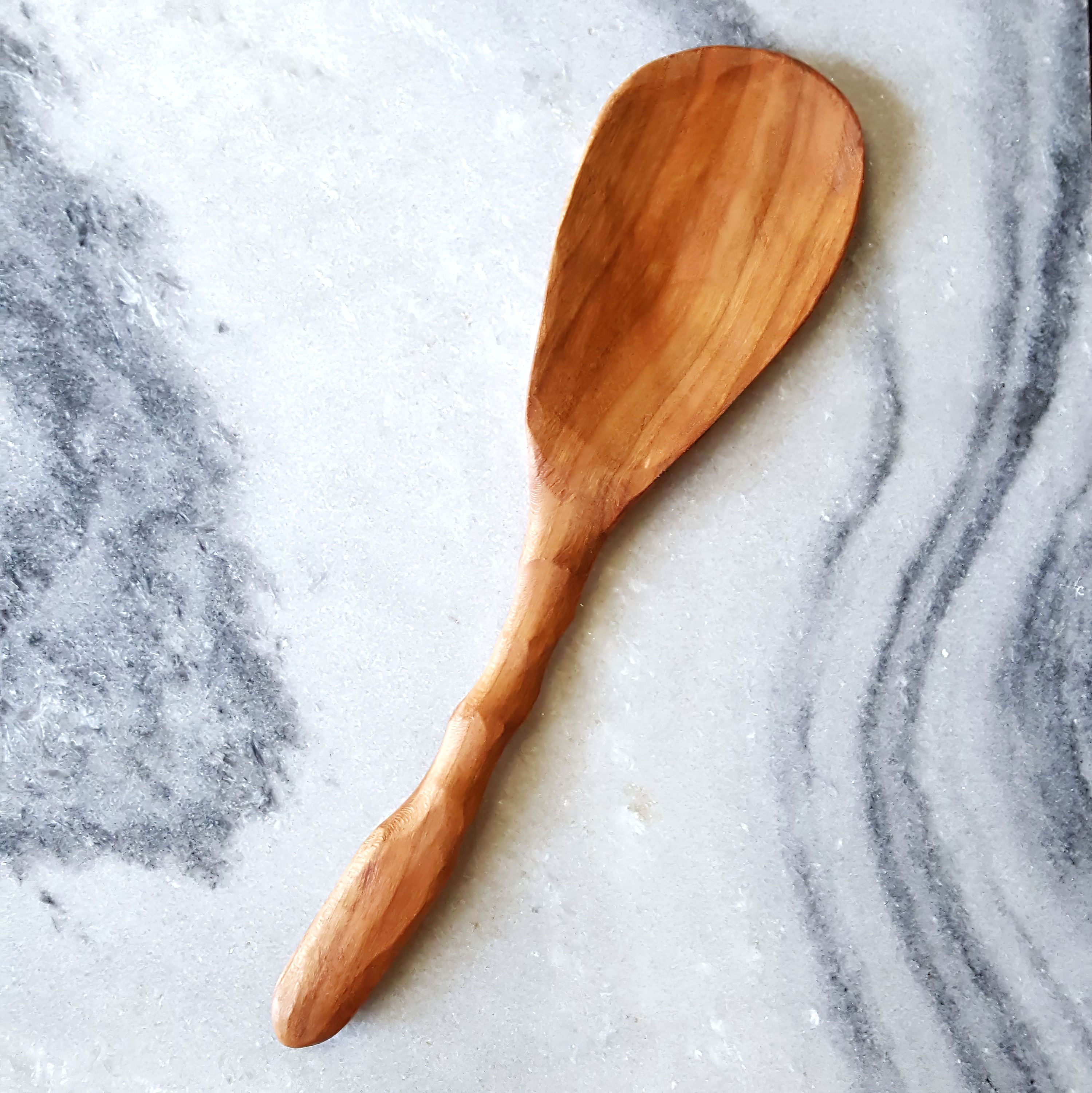 A wooden rice paddle with a thin, shallow bowl and slender handle, available in Cherry and Walnut finishes.