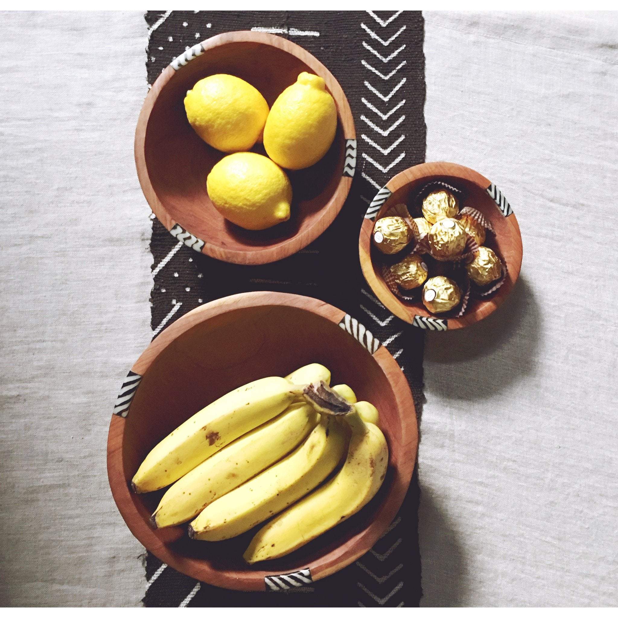 A beautifully handcrafted set of three African olive wood salad and fruit bowls, showcasing unique grain patterns and batik cow bone decoration.