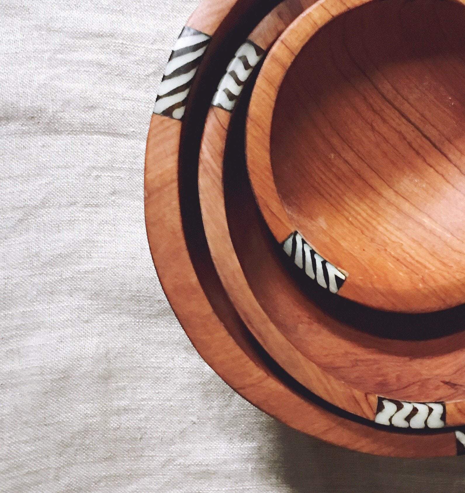 A beautifully handcrafted set of three African olive wood salad and fruit bowls, showcasing unique grain patterns and batik cow bone decoration.