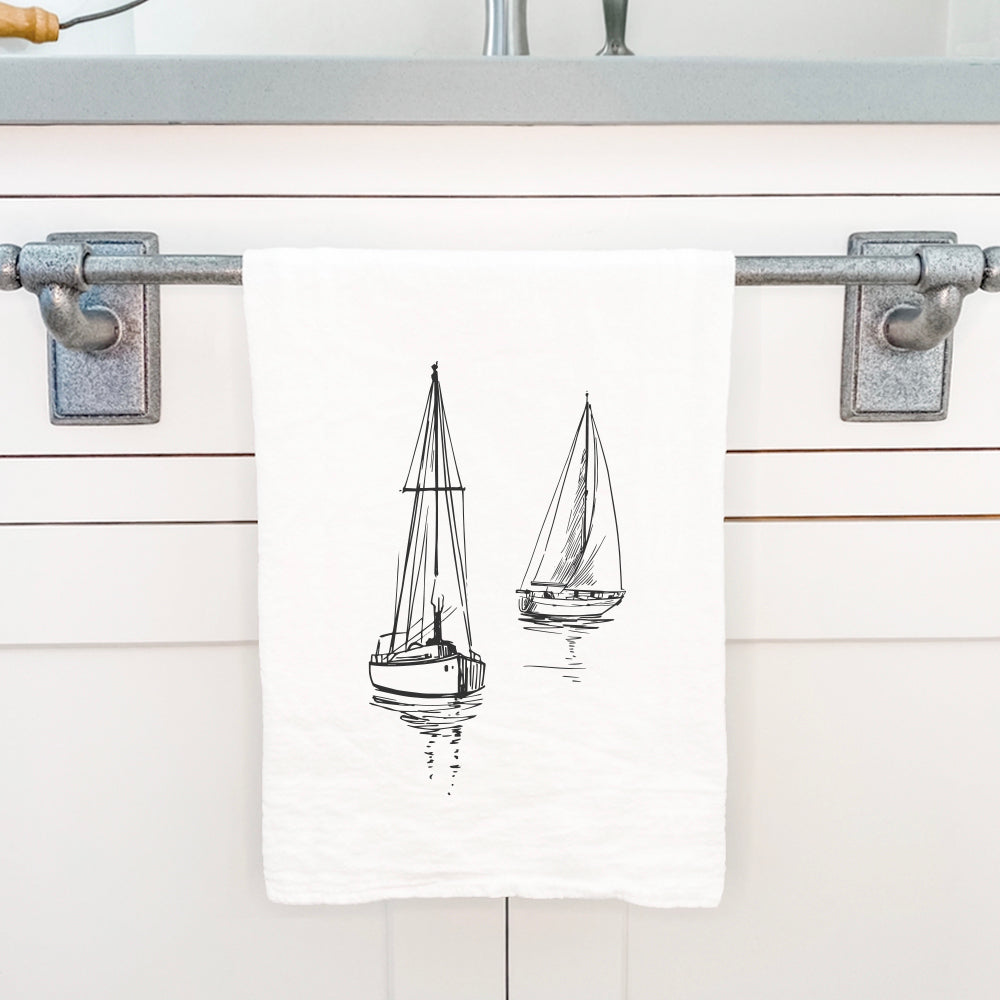 A beautifully designed cotton tea towel featuring sketched sailboats, showcasing vibrant colors and hemmed edges.