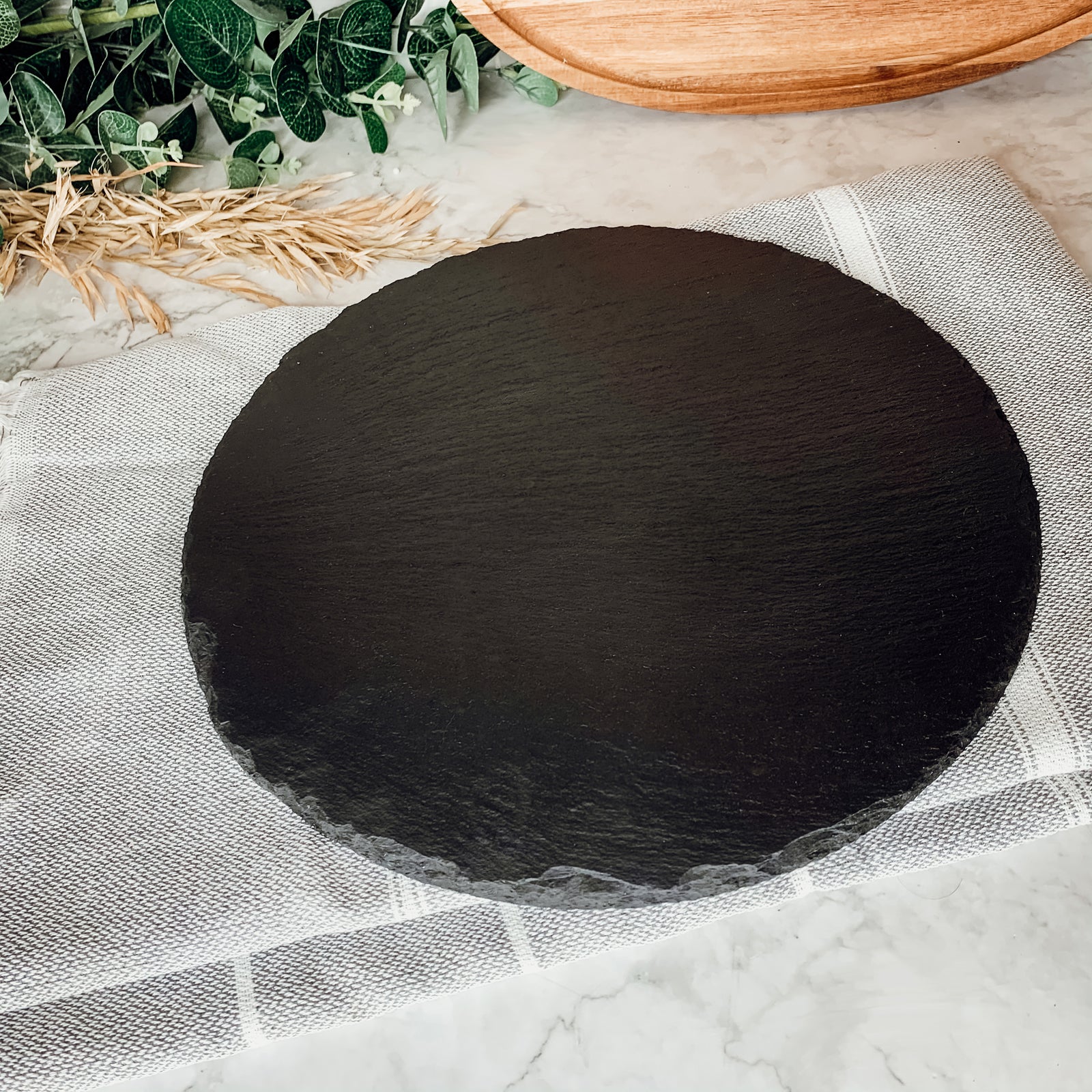 11-inch round slate cheese board with natural edges, perfect for serving appetizers and cheeses.