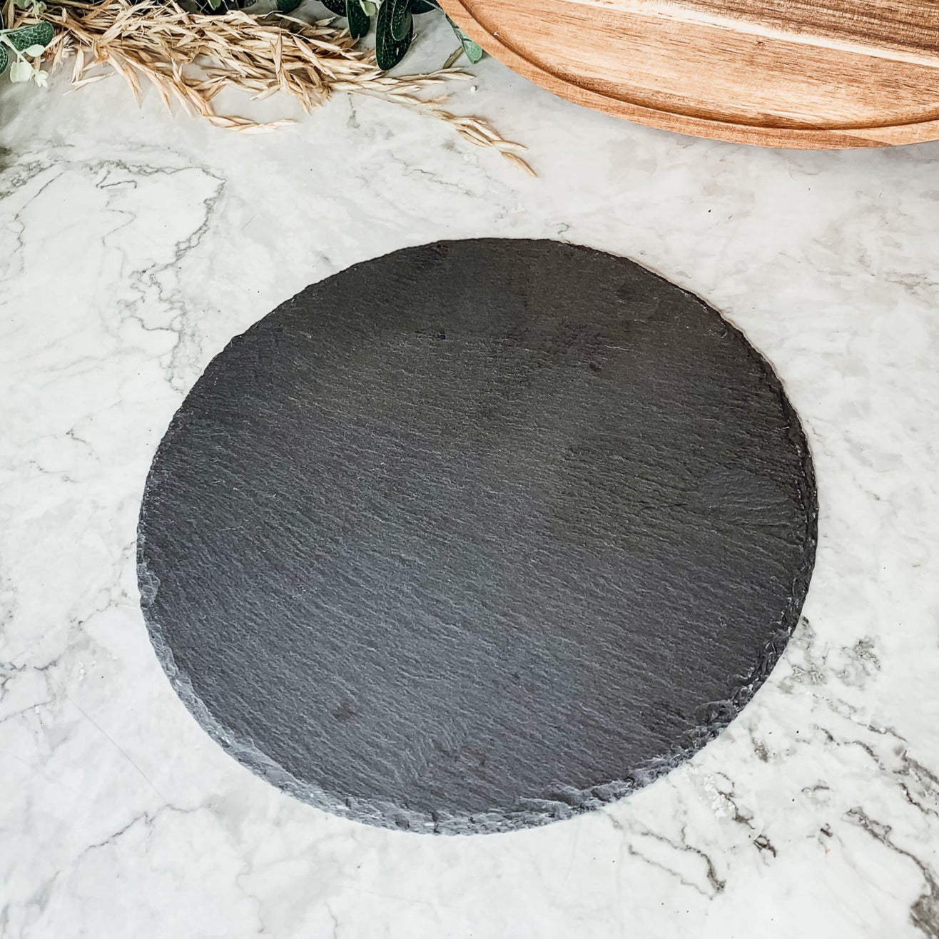 11-inch round slate cheese board with natural edges, perfect for serving appetizers and cheeses.