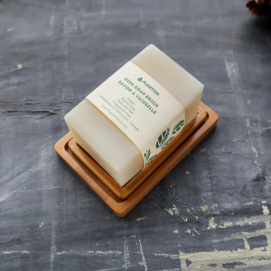 Solid Dish Soap Brick (13oz) displayed on a bamboo soap dish, showcasing its eco-friendly packaging and natural ingredients.