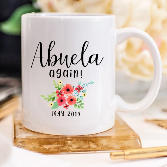 A charming white ceramic mug featuring a vibrant design celebrating Abuela, perfect for coffee or tea.