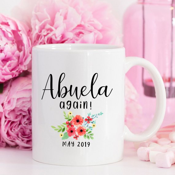 A charming white ceramic mug featuring a vibrant design celebrating Abuela, perfect for coffee or tea.