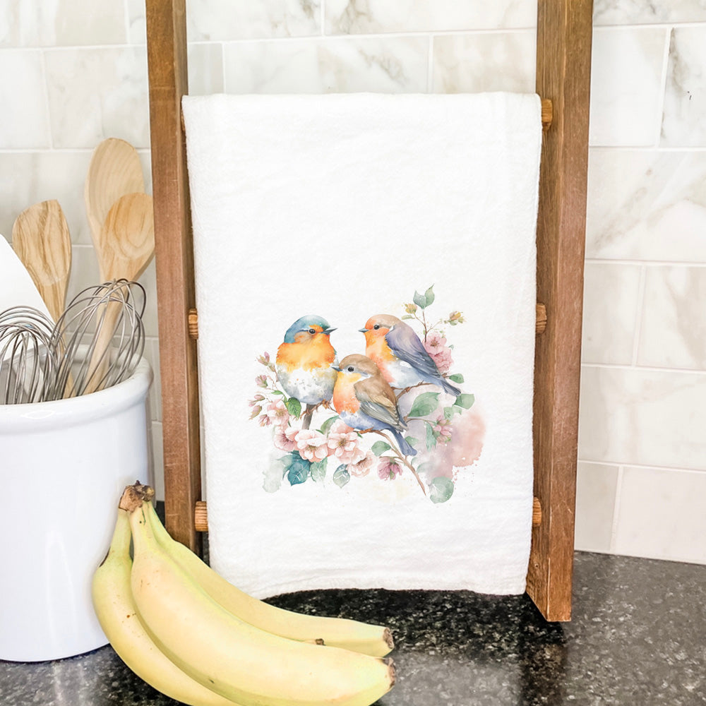 A vibrant cotton tea towel featuring a watercolor design of spring birds, showcasing colorful illustrations on a white background.