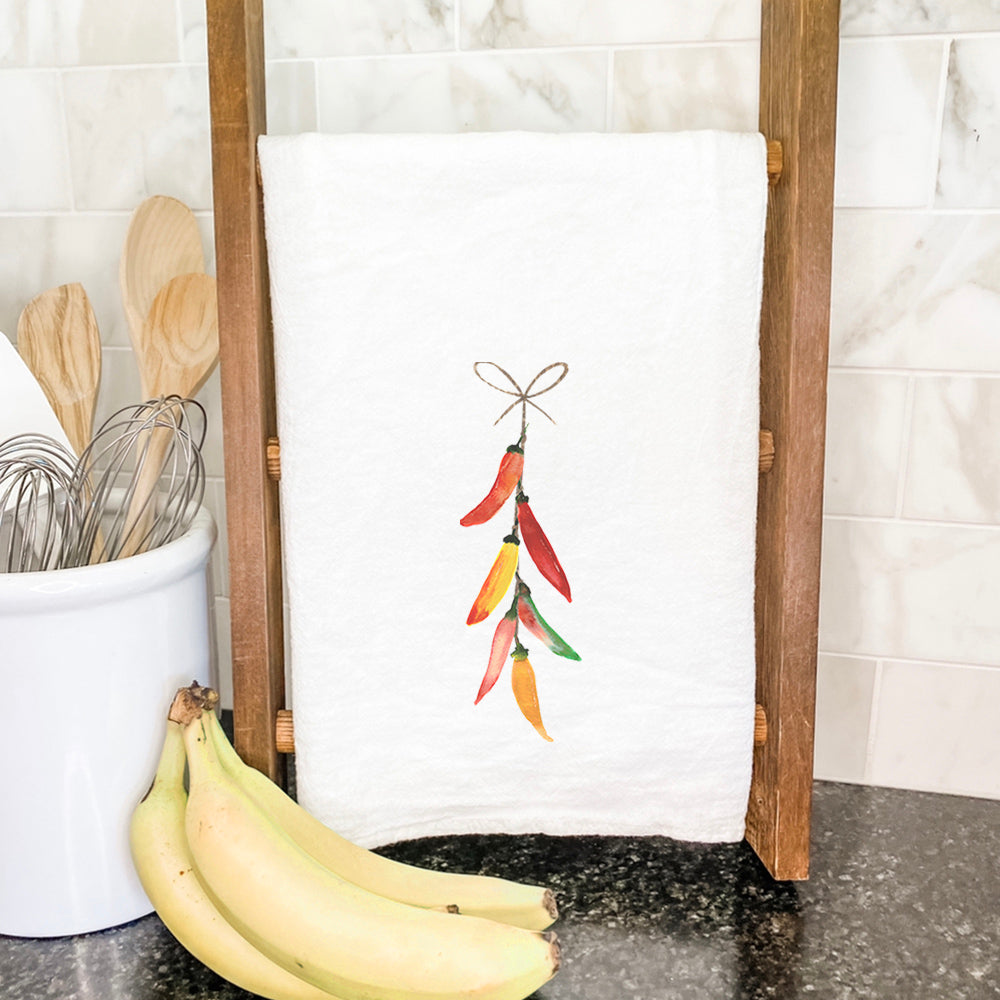 A vibrant cotton tea towel featuring a String of Peppers design, perfect for kitchen use.