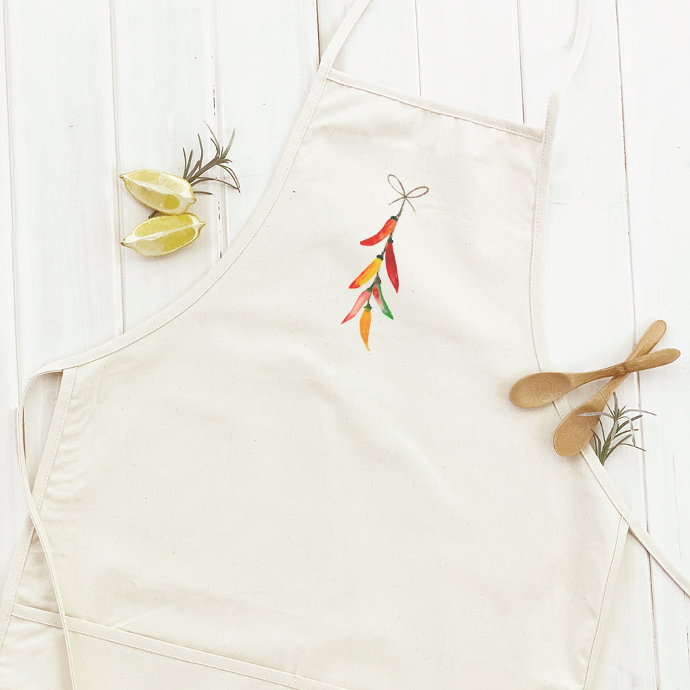 A stylish String of Peppers Women's Apron made from durable cotton canvas, featuring natural twill ties and a divided front pocket.