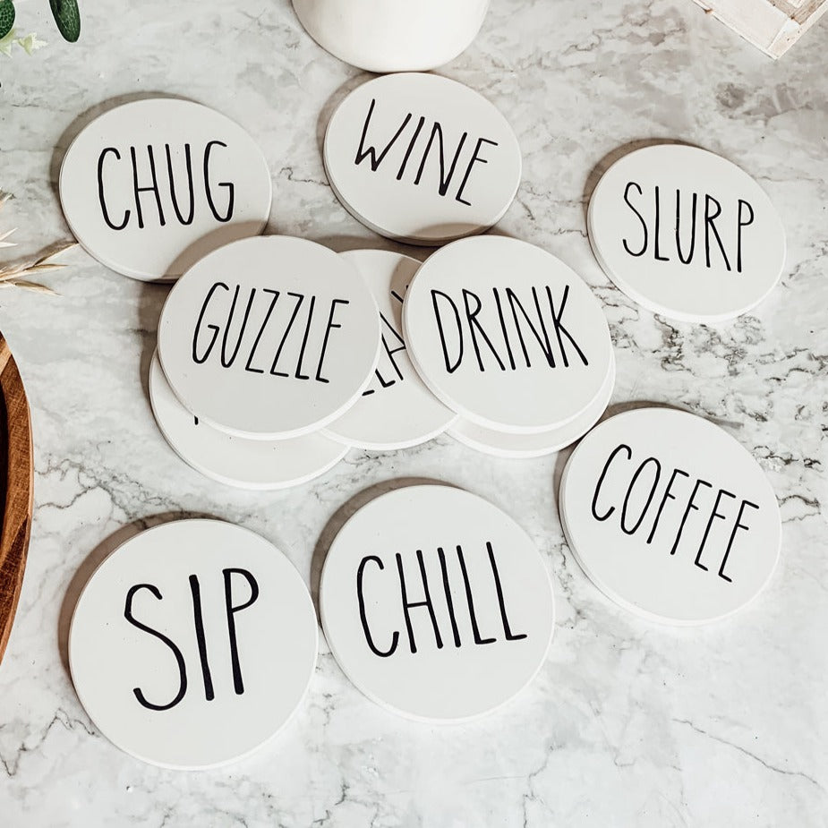 A stylish set of ceramic coasters with cork backing, featuring various fun designs for kitchen decor.