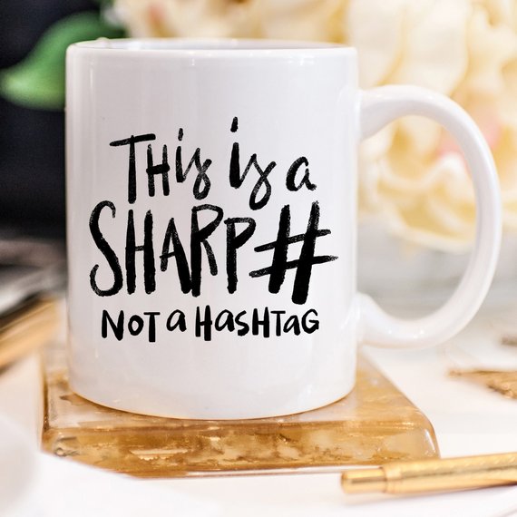 A humorous coffee mug with the phrase 'This Is A Sharp, Not A Hashtag' printed on it, showcasing a playful design suitable for coffee lovers.