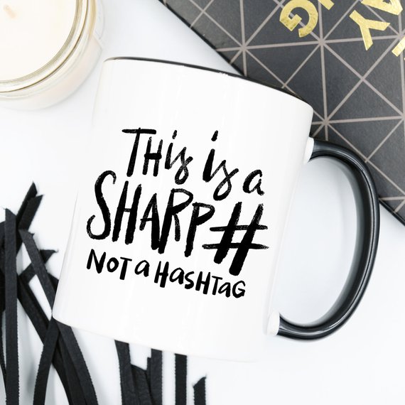 A humorous coffee mug with the phrase 'This Is A Sharp, Not A Hashtag' printed on it, showcasing a playful design suitable for coffee lovers.